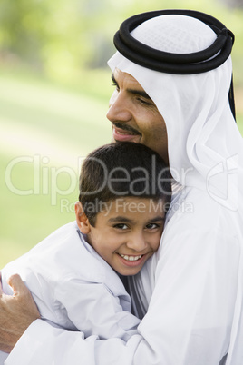 A Middle Eastern man and his son sitting in a park