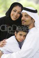 A Middle Eastern couple and their son sitting in a park