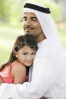 A Middle Eastern man and his daughter sitting in a park