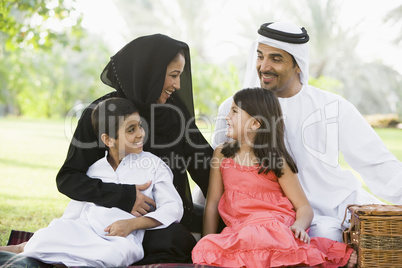 A Middle Eastern family sitting in a park