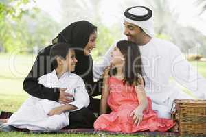 A Middle Eastern family sitting in a park