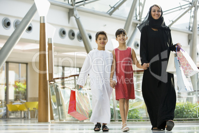 A Middle Eastern woman with two children in a shopping mall