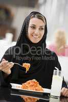 A Middle Eastern woman enjoying a meal in a restaurant