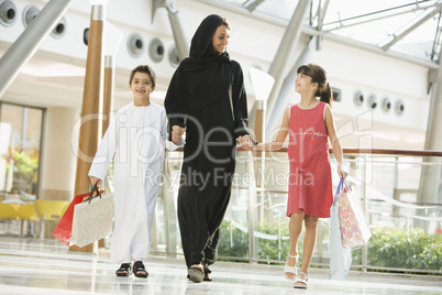 A Middle Eastern woman with two children in a shopping mall