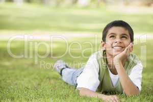 Junge liegt im Gras und schaut zum Himmel