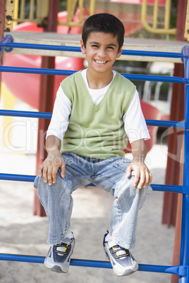 Ein Junge lachend auf einem Klettergerüst
