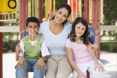 Eine Mutter sitzt mit Ihren Kindern auf einer Bank