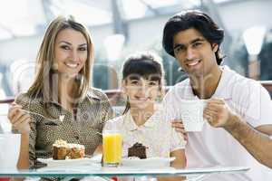 Young family having coffee and cake