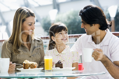 Young family having coffee and cake