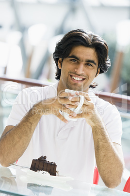 Young man having coffee and cake