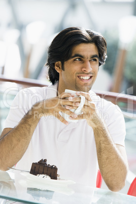 Young man having coffee and cake