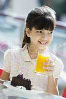 Young girl having orange juice and cake