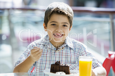 Young boy having orange juice and cake