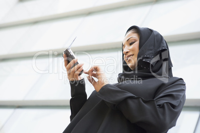 A Middle Eastern businesswoman using a PDA