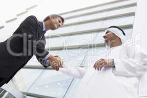 A Middle Eastern businessman shaking hands with a Caucasian busi
