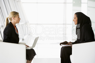 A Middle Eastern businesswoman talking to a Caucasian businesswo