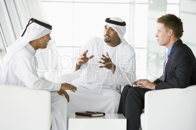 A meeting between a Caucasian businessman and two Middle Eastern