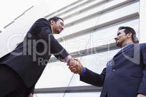 Two businessmen shaking hands outside office building