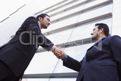 Two businessmen shaking hands outside office building