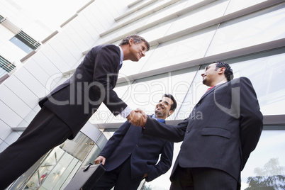 Group of businessmen shaking hands outside office