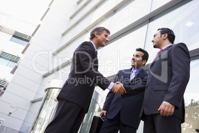 Group of businessmen shaking hands outside office