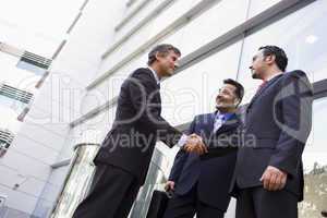 Group of businessmen shaking hands outside office