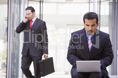 Businessman working at laptop outside