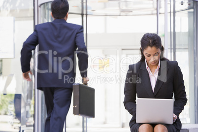 Businesswoman working at laptop outside
