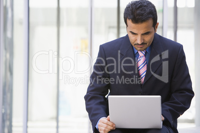 Businessman using laptop outside office