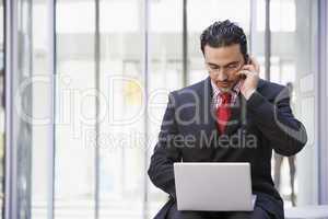 Businessman using laptop and mobile outside