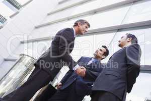 Group of businessmen shaking hands outside office