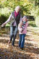 Grandmother and granddaughter walking in the forrest in fall time
