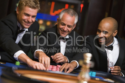 Drei Männer im Anzug spielen Roulette