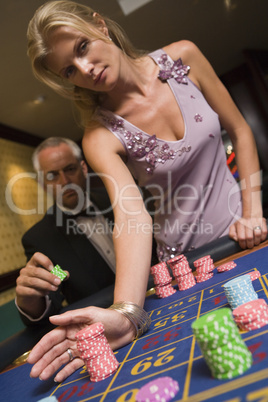 Eine Frau verschiebt Chips auf einem Roulettetisch