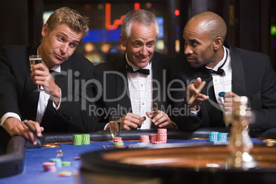 Drei Männer im Anzug spielen Roulette