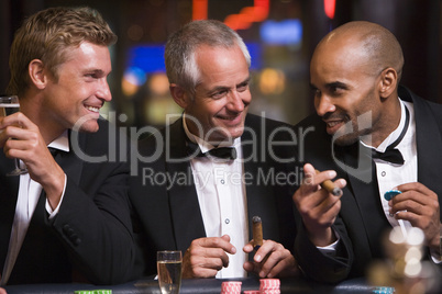 Drei Männer im Anzug sitzen am Roulettetisch