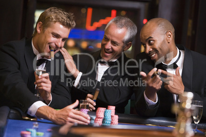 Drei Männer im Anzug sitzen am Roulettetisch