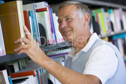 Senior man pulling a library book off shelf