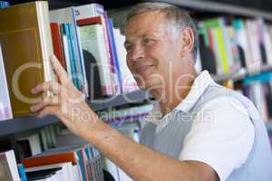 Senior man pulling a library book off shelf