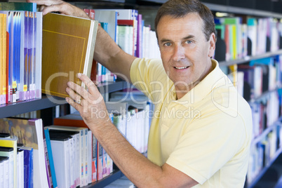 Man pulling a library book off shelf