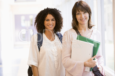 Two women with backpacks standing in a campus corridor