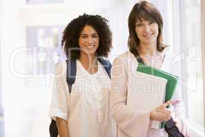 Two women with backpacks standing in a campus corridor