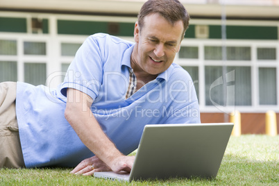 Man using laptop while lying in grass on campus