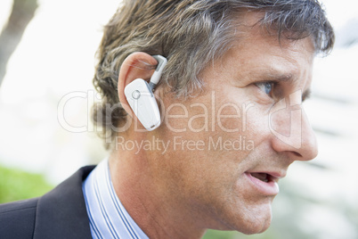 Businessman wearing earpiece outdoors