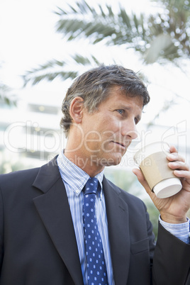 Businessman outdoors drinking coffee