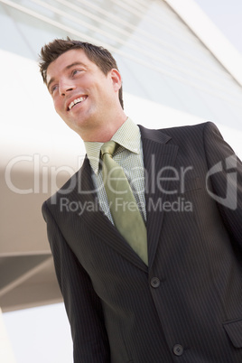 Businessman standing outdoors by building smiling