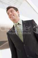 Businessman standing outdoors by building smiling