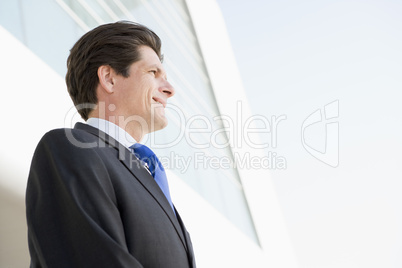 Businessman standing outdoors by building smiling