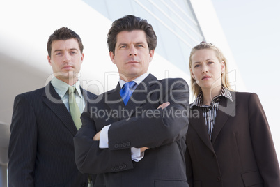 Three businesspeople standing outdoors by building