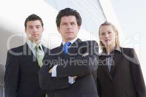 Three businesspeople standing outdoors by building